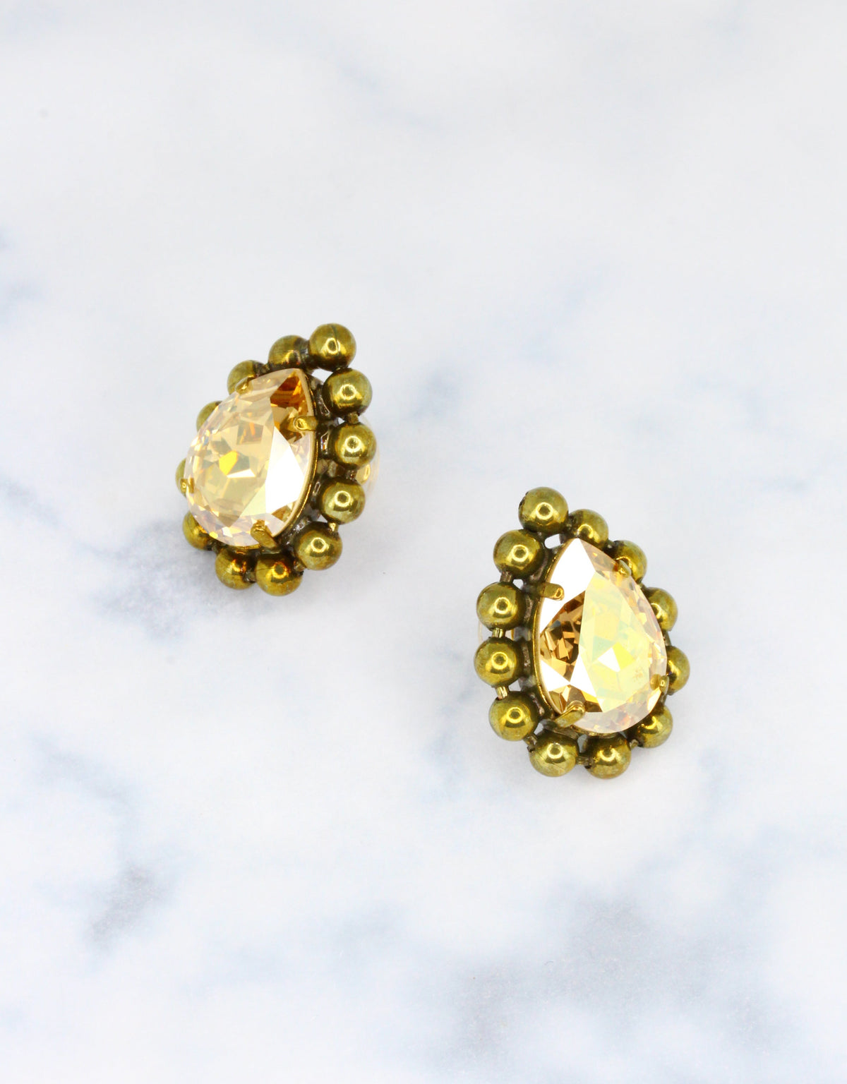 A pair of vintage earrings with a metal ball chain and a central genuine crystal in a pear shape, encircled by gold-colored metal.