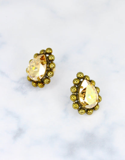 A pair of vintage earrings with a metal ball chain and a central genuine crystal in a pear shape, encircled by gold-colored metal.