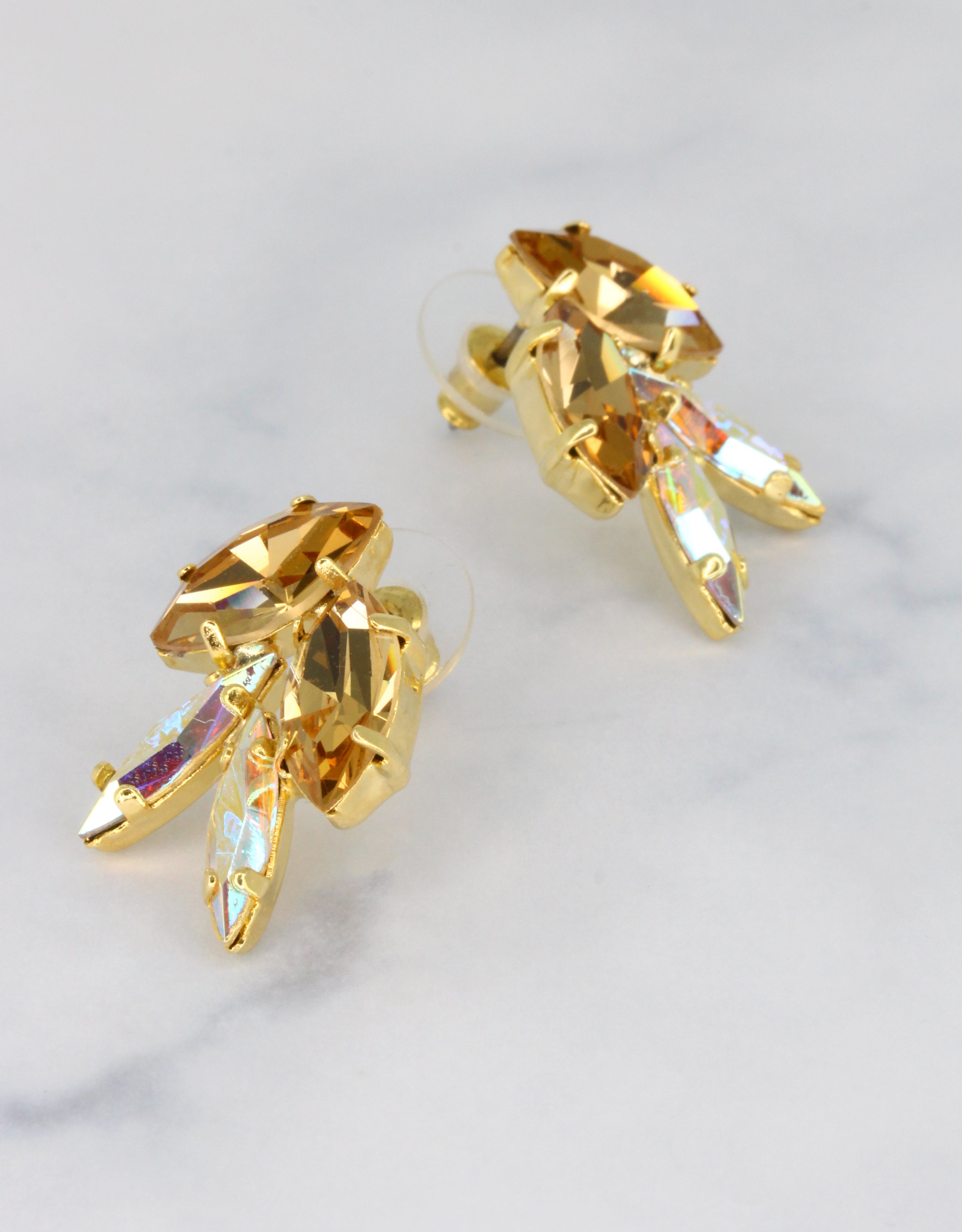 A pair of gold-colored earrings featuring marquise-shaped crystals with a unique artistic design.