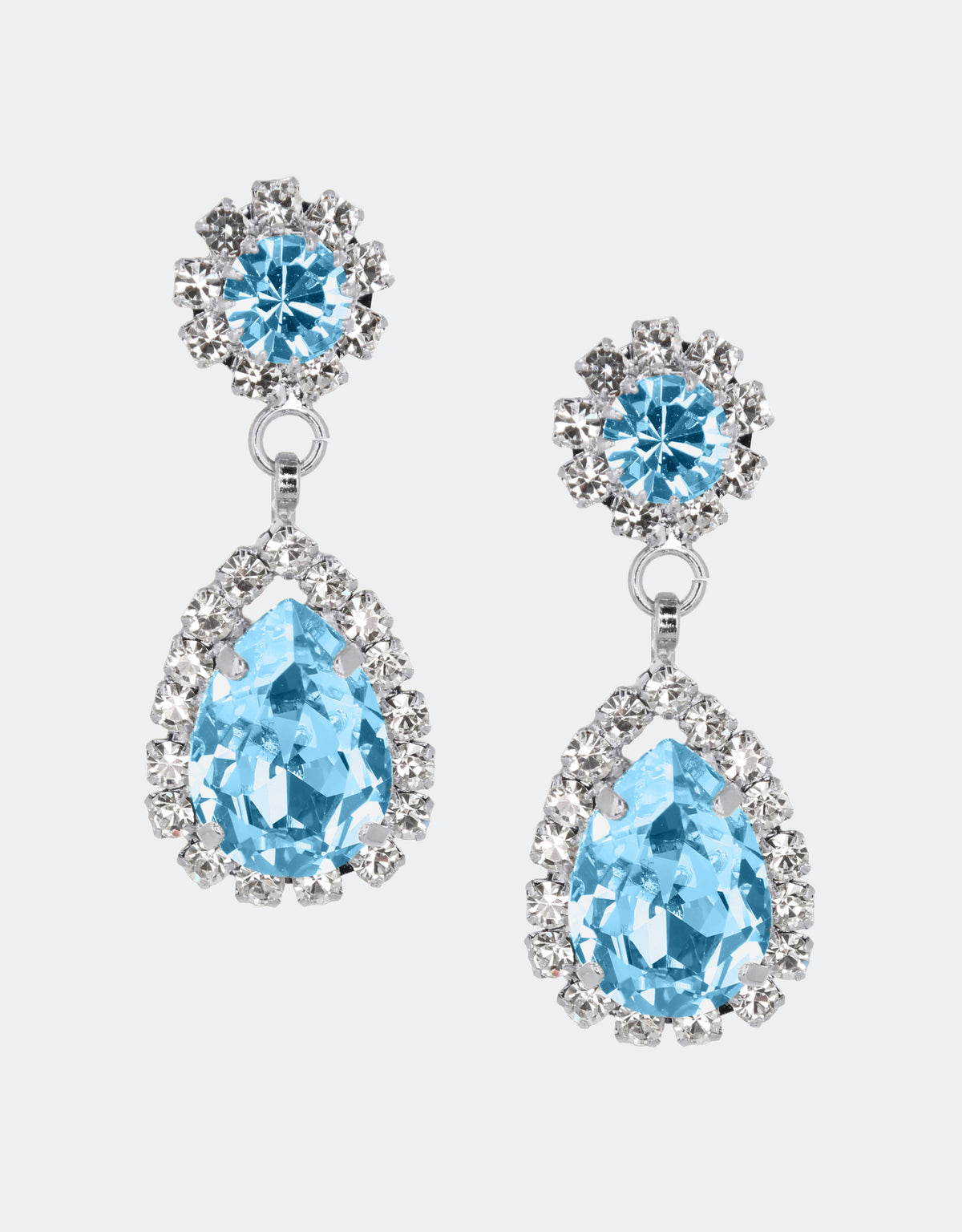 A pair of Rosa earrings with delicate blue crystals surrounding a round and pear shaped crystal, in gold color.
