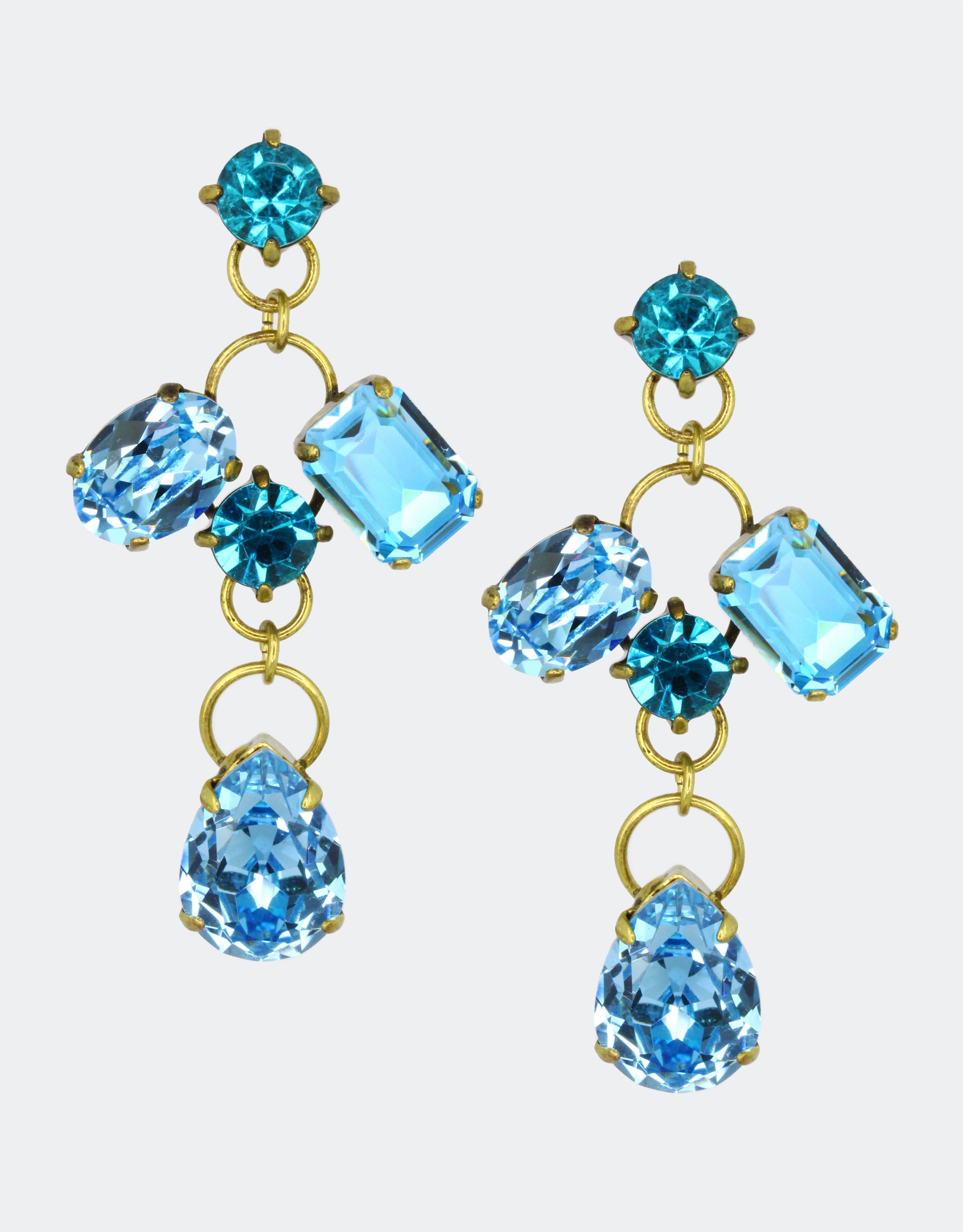 A pair of vintage earrings with pear-shaped crystals in blue and other geometric shapes, mounted on gold-colored metal.