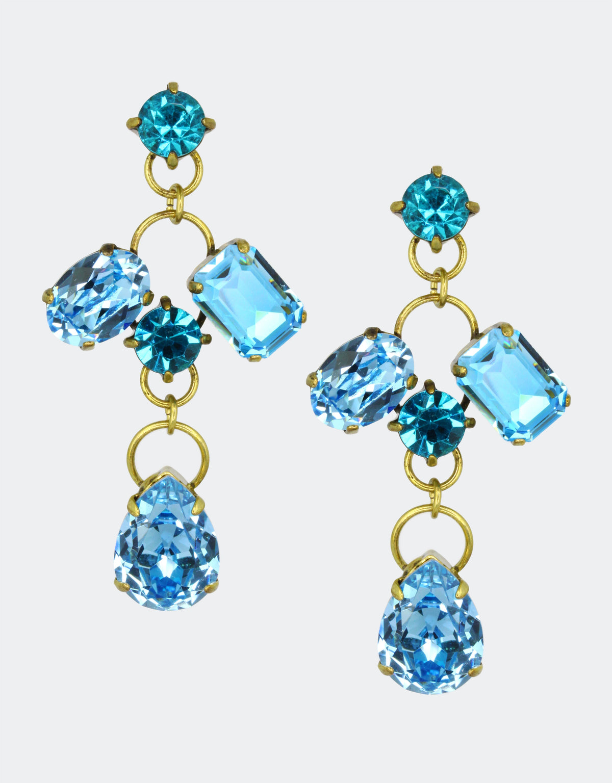 A pair of vintage earrings with pear-shaped crystals in blue and other geometric shapes, mounted on gold-colored metal.