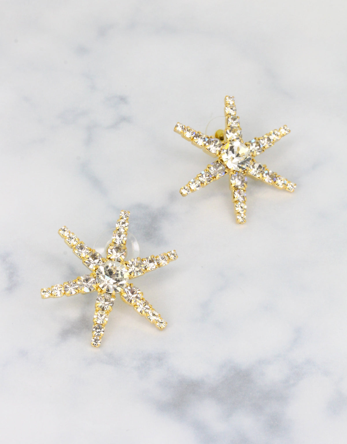 A pair of gold-colored starfish-shaped earrings adorned with crystals a fine summer beach jewellery